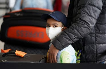 A boy wearing a face mask stands in the check-in line with his family at Dulles International Airport a day after U.S. President Donald Trump announced travel restrictions on flights from Europe to the United States for 30 days to try to contain coronavirus, in Dulles, Virginia, U.S., March 12, 2020. (Reuters)