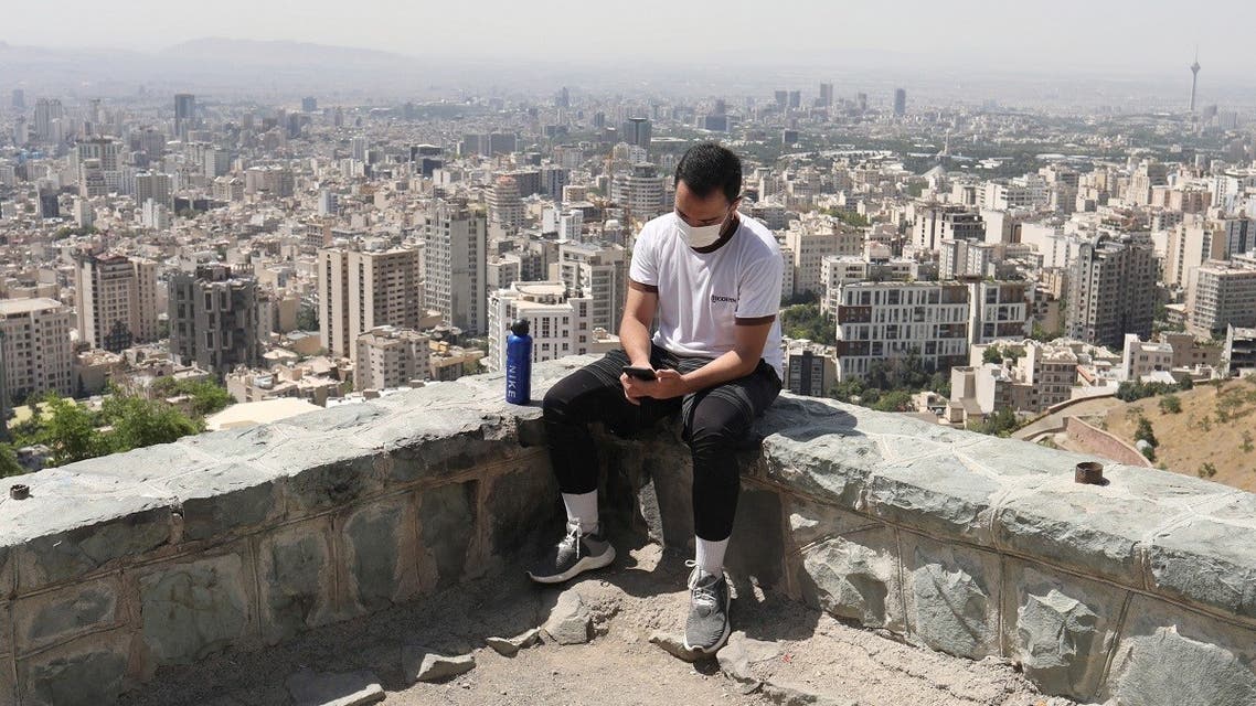 An Iranian man wearing a protective face mask checks his mobile in Baam-e, following the outbreak of the coronavirus disease (COVID-19), in Tehran. (Reuters)