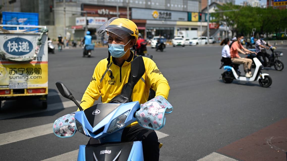 A food delivery driver wearing a face mask rides an electric bicycle across a street in Beijing on June 19, 2020. Travel restrictions were placed on nearly half a million people near Beijing on June 18 as authorities rushed to contain a fresh outbreak of the coronavirus with a mass test-and-trace effort and lockdowns in parts of the Chinese capital.