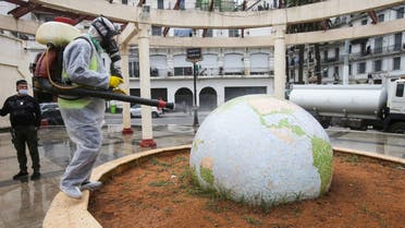 A worker wearing a protective suit disinfects a globe-shaped public garden, following the outbreak of coronavirus, in Algiers, Algeria, March 23, 2020. (Reuters)