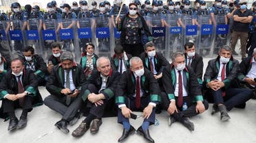 Senior lawyers protesting against a draft bill governing the organisation of bar associations sit on the ground during a rally in front of Turkish riot policemen blocking the road, in Ankara on June 22, 2020. (AFP)