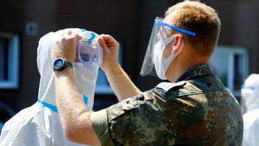 A member of the German Army adjusts the googles of a health professional outside the houses of employees of the Toennies factory, who are under lockdown after a coronavirus disease (COVID-19) outbreak in the meatpacking plant, in Verl, Germany, June 23, 2020. REUTERS/Leon Kuegeler