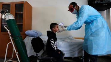 A Palestinian health worker checks the body temperature of a child at a UNRWA school at al-Shati refugee camp in Gaza City on March 18, 2020. (AFP)