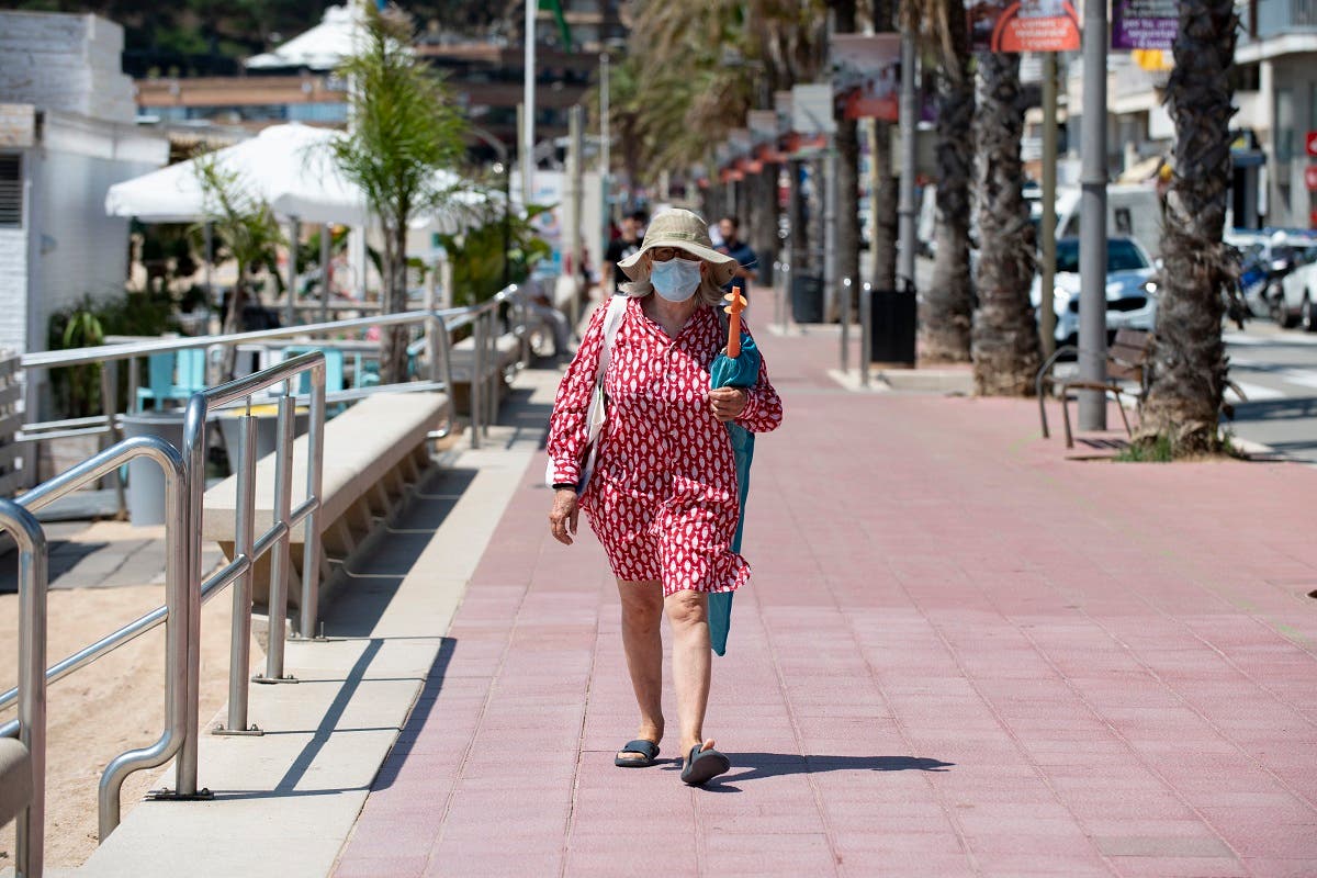 A woman wearing a face mask walks in Lloret de Mar on June 22, 2020 as beaches reopen in Spain. (AFP)