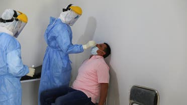 A member of a medical team wearing a protective suit takes a swab to test for the coronavirus disease (COVID-19) at a medical clinic in Tripoli, Libya June 10, 2020. REUTERS/Ismail Zitouny