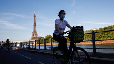 A woman wearing a protective mask rides a Velib bicycle-sharing service near the Eiffel Tower during a warm and sunny day in Paris as a heatwave hits France, June 24, 2020. (Reuters)