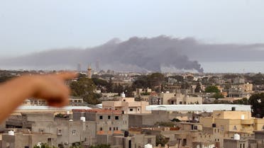 A finger points at smoke rising above buildings in the Libyan capital Tripoli, during reported shelling on May 9, 2020. (AFP)