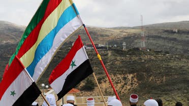 Members of the Druze community holds Syrian and Druze flags as they sit facing Syria, during a rally marking the anniversary of Israel's annexation of the Golan Heights in the Druze village of Majdal Shams, in the Israeli-occupied Golan Heights February 14, 2019. (Reuters)