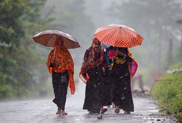 Villagers hold umbrellas and walk in the rain in Morigaon district of Assam, India, Friday, June 26, 2020. (AP)