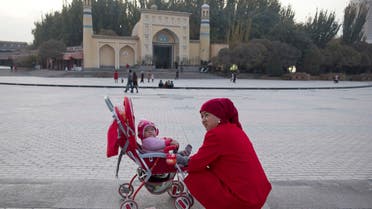 a woman tends to her child near the Id Kah Mosque in Kashgar in western China's Xinjiang region. (AP)