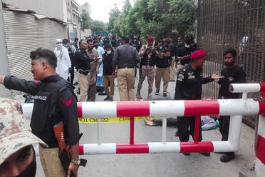Policemen secure an area around a body outside the Pakistan Stock Exchange building after a group of gunmen attacked the building in Karachi. (AFP)