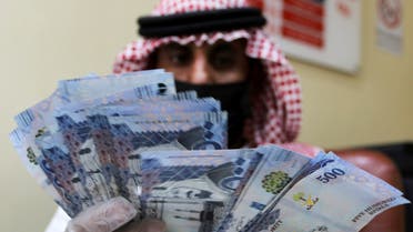 A Saudi money exchanger wears gloves as he counts Saudi riyal currency at a currency exchange shop in Riyadh, Saudi Arabia, March 10, 2020. (Reuters)