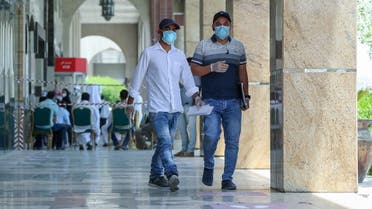 People wearing protective gear walk by on a street of Qatar's capital Doha, on May 17, 2020. (AFP)