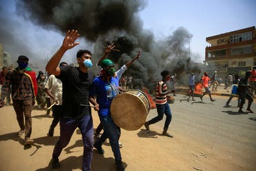 Sudanese demonstrators carrying a drum gesture as smoke billows from burning tires during a protest on Sixty street in the east of the capital Khartoum, on June 30, 2020. (AFP)