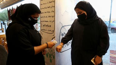 A restaurant's female member of the security personnel wearing a protective face mask, following the outbreak of the coronavirus disease (COVID-19), checks the temperature of a woman before enter the restaurant after reopened, in Riyadh, Saudi Arabia June 13, 2020. Picture taken June 13, 2020. REUTERS/Ahmed Yosri