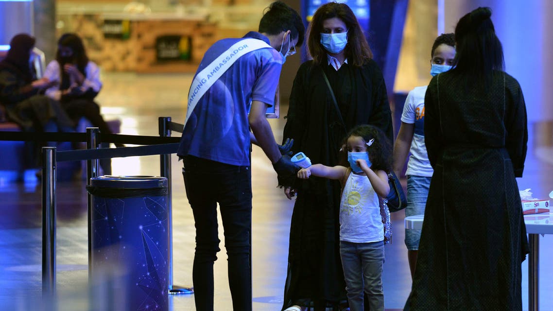 A man measures the temperature of a child as a family enter a movie theatre at a cinema in the Saudi capital Riyadh, on June 22, 2020 as cinemas re-opened following the lifting of a lockdown due to the COVID-19 coronavirus pandemic.
