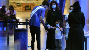 A man measures the temperature of a child as a family enter a movie theatre at a cinema in the Saudi capital Riyadh, on June 22, 2020 as cinemas re-opened following the lifting of a lockdown due to the COVID-19 coronavirus pandemic. 