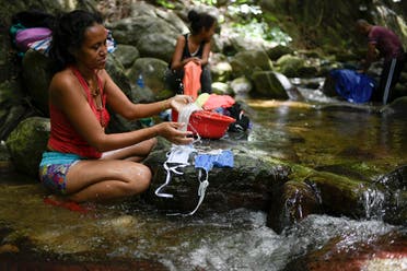 A woman washes her protective face masks with runoff water from the Avila mountain in Caracas, Venezuela on June 21, 2020. (AP)