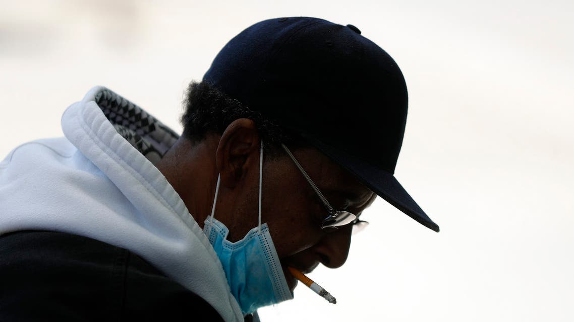 A man smokes a cigarette while wearing a protective mask while waiting for a bus in Detroit. (AP)