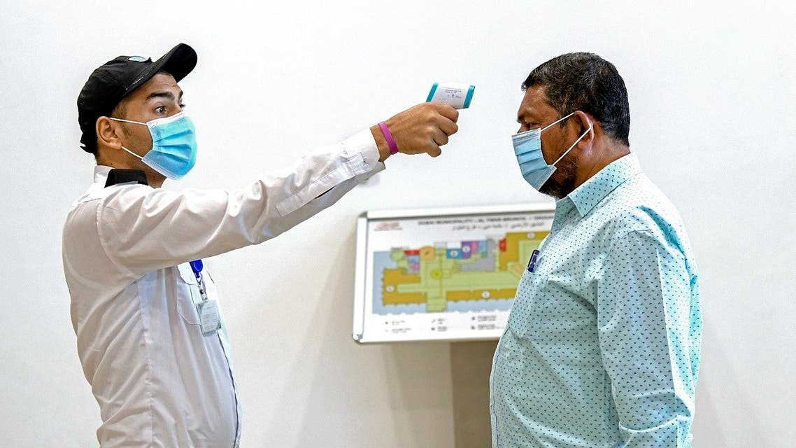 An Emirati security guard checks a visitor's temperature at the Passports Department as civil servants return to work following the easing of restrictions in Dubai on 16 June, 2020. (AFP)