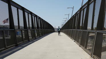 FILE PHOTO: A lone pedestrian walks across the pedestrian bridge at the U.S.-Mexico border during the coronavirus disease (COVID-19) outbreak in San Diego, California, U.S., April 21, 2020. REUTERS/Mike Blake - RC289G9G101X/File Photo