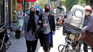 Iranian pedestrians wearing protective masks due to the COVID-19 pandemic, walk along a street in the capital Tehran on July 1, 2020. 