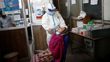 A health worker in personal protective equipment (PPE) collects a sample using a swab from a girl at a local health centre to conduct tests for the coronavirus disease (COVID-19), amid the spread of the disease, in New Delhi, India July 4, 2020. REUTERS/Adnan Abidi