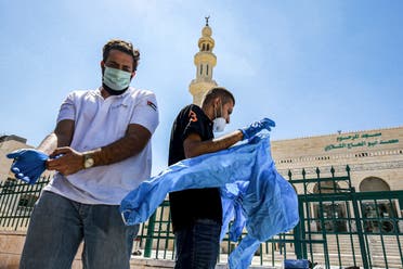 Workers suit up in PPE (personal protective equipment) before sterilizing a mosque in Jordan's capital Amman on June 3, 2020. (AFP)