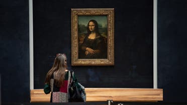 a woman in front of Italian artist Leonardo da Vinci's Mona Lisa at the Louvre in Paris, during a press visit of the museum. (AFP)