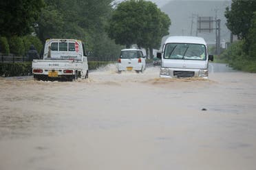 Vehicles pass through a flooded road caused by heavy rain in Yatsushiro, Kumamoto prefecture on July 4, 2020. (AFP)