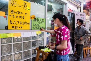 A woman (L) sticks a blank note onto a “Lennon Wall” outside a pro-democracy restaurant in Hong Kong on July 3, 2020, in response to the new national security law. (AFP)