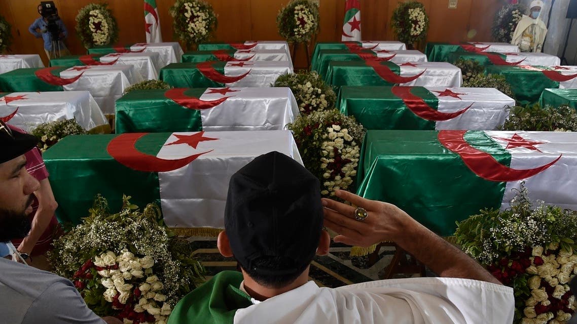 An Algerian man pays respect in front of the national flag-draped coffins containing the remains of 24 Algerian resistance fighters decapitated during the French colonial conquest of the North African country, presented at the capital's Palais De La Culture Moufdi Zakaria on July 4, 2020, a day after they were flown in from France. (AFP)