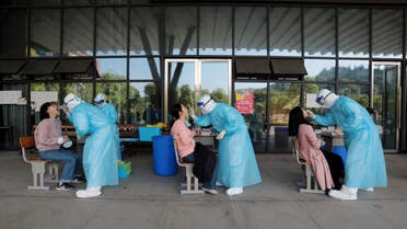 Medical workers collect swabs from high school teachers for nucleic acid tests at a school in Yichang. (Reuters)
