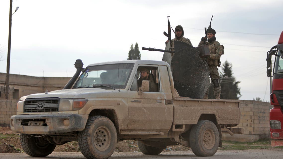 Turkish-backed Syrian fighters ride in the back of a truck fitted with an anti-aircraft gun as they patrol along a street in the northern Syrian town of Tal Abyad by the border with Turkey on February 4, 2020.