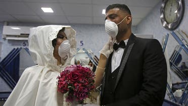 Newly-wed Palestinians Eshaq Musleh (R) and Shayma Titi, both wearing protective masks during the COVID-19 coronavirus pandemic. (AFP)