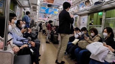 Commuters wearing face masks travel on a subway train in Tokyo on May 7, 2020. 