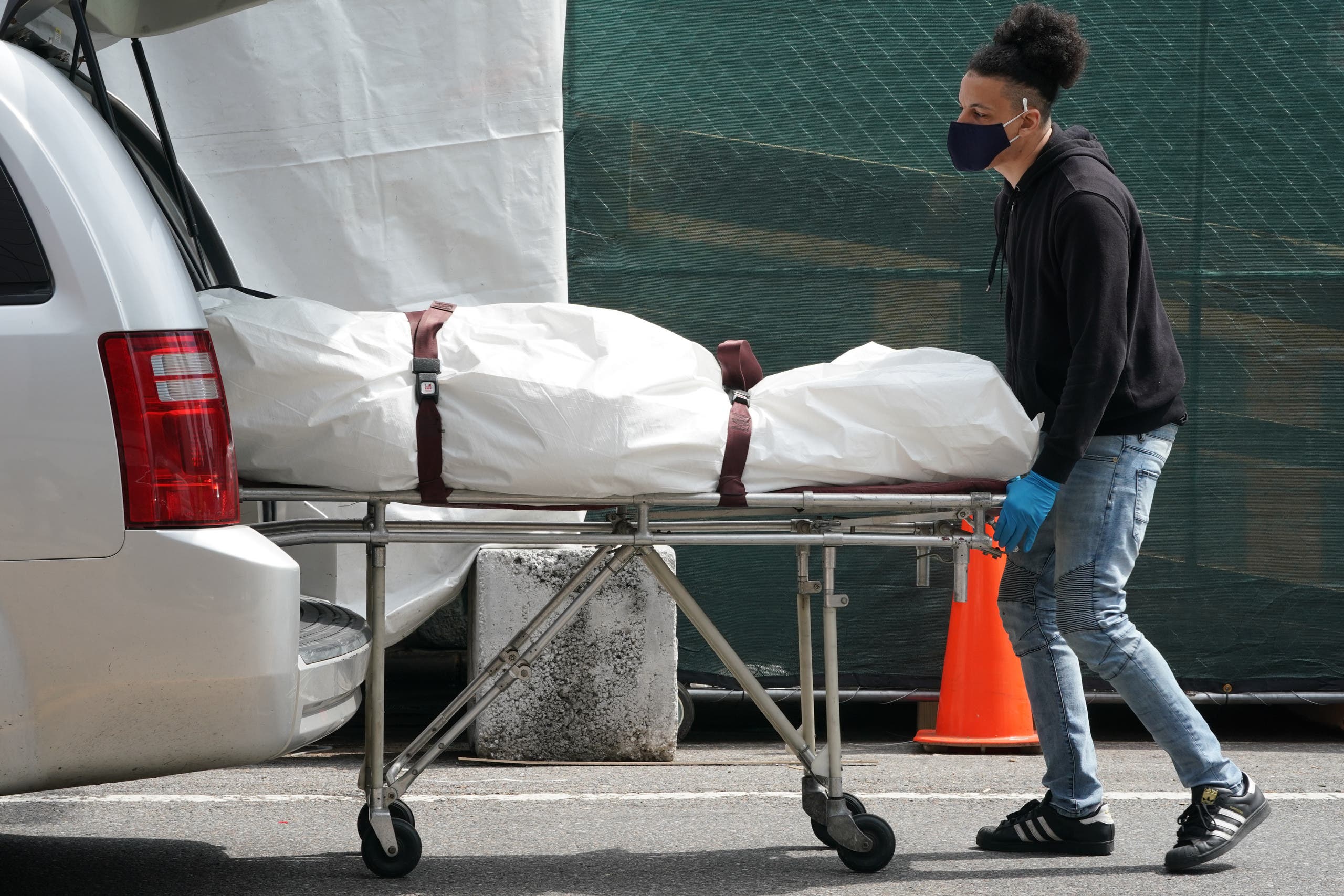 In this file photo taken on April 8, 2020, a body is moved from a refrigeration truck serving as a temporary morgue to a vehicle at the Brooklyn Hospital Center, in the Borough of Brooklyn in New York. (AFP)