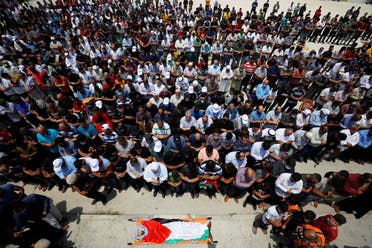 Mourners pray before the body of Palestinian man Ibraheem Yakoub during his funeral in Kifl Haris in the Israeli-occupied West Bank on July 10, 2020. (Reuters)