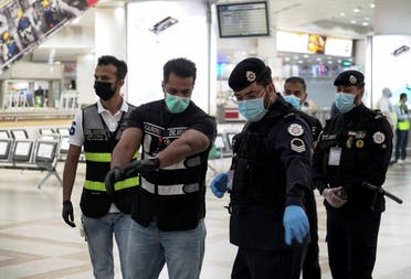 Police and civil aviation personnel wearing protective face masks work at the Kuwait Airport following the outbreak of the coronavirus. (Reuters)