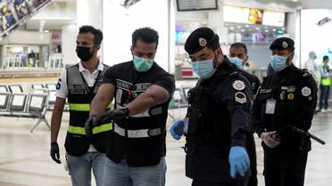 Police and civil aviation personnel wearing protective face masks work at the Kuwait Airport following the outbreak of the coronavirus. (Reuters)