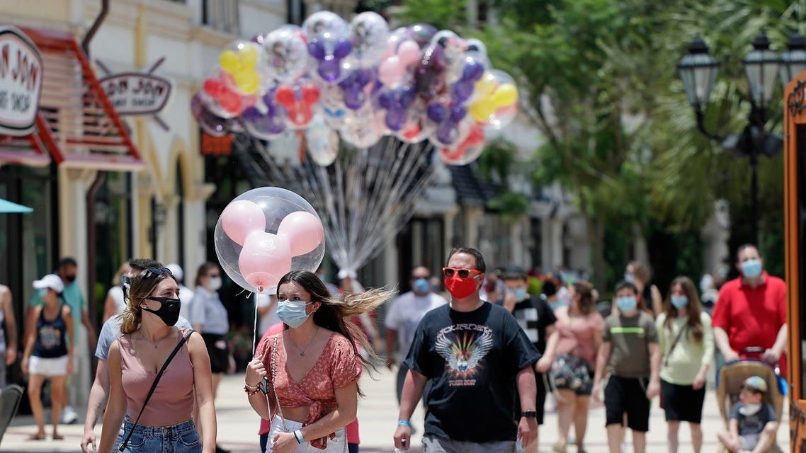 guests required to wear masks because of the coronavirus stroll through the Disney Springs shopping, dining and entertainment complex in Lake Buena Vista, Flaorida. (AP)