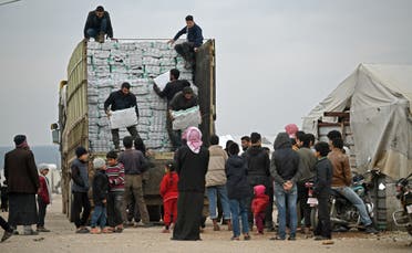 Displaced Syrians queue to receive humanitarian aid at a camp in the town of Mehmediye, near the town of Deir al-Ballut along the border with Turkey, on February 21, 2020. (AFP)