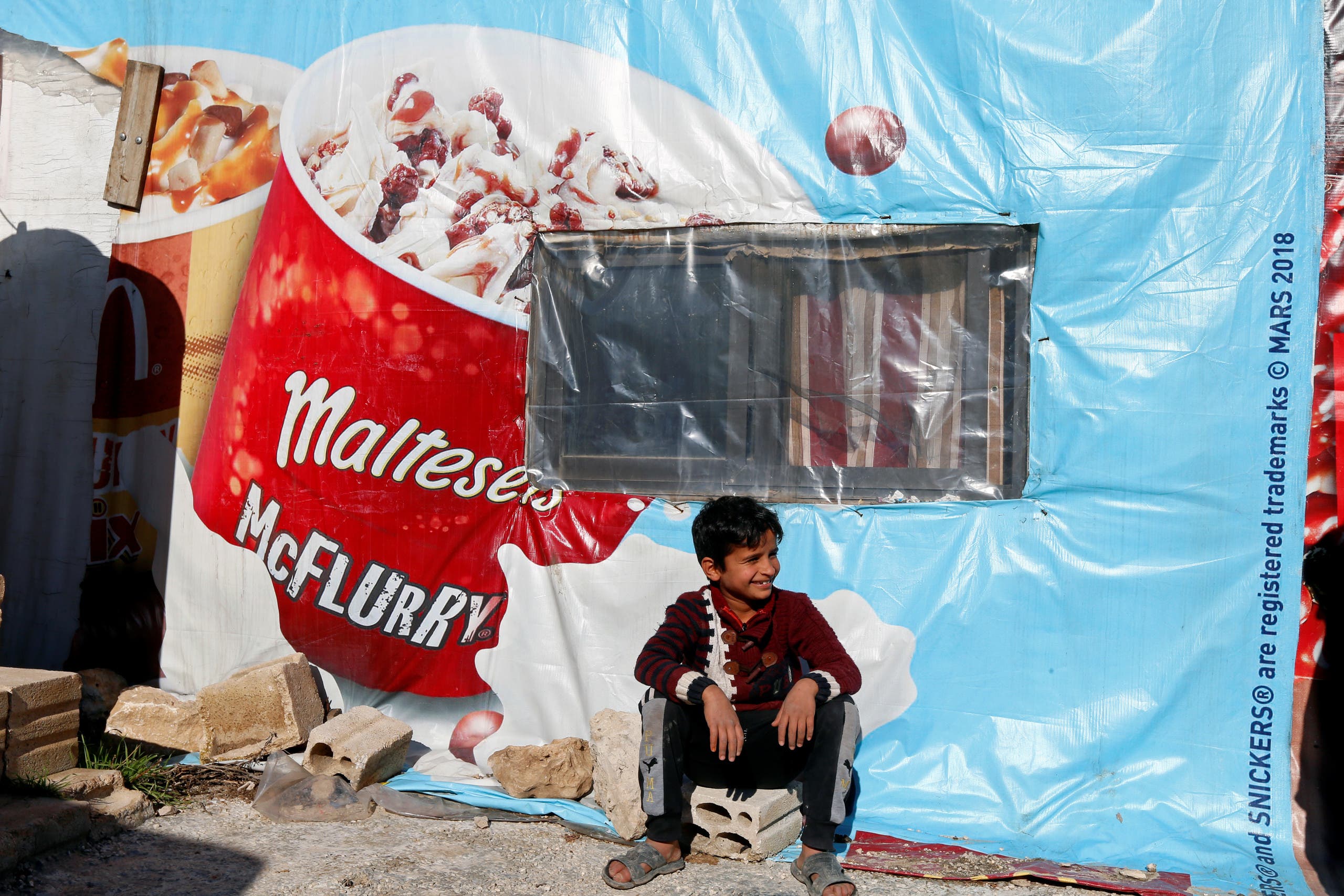 A Syrian refugee boy sits outside a tent at a camp in Bar Elias, in the Bekaa Valley, Lebanon Jan. 13, 2020. (Reuters)