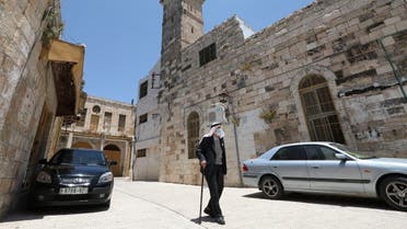 A Palestinian man wearing a protective face mask walks past the closed al-Qazazin mosque in the Old City of the West Bank town of Hebron. (AFP)