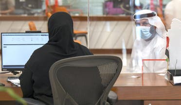 An Emirati civil employee tends to a visitor at the Passports Department as government employees return to work following the easing of restrictions in Dubai on 16 June, 2020. (AFP)