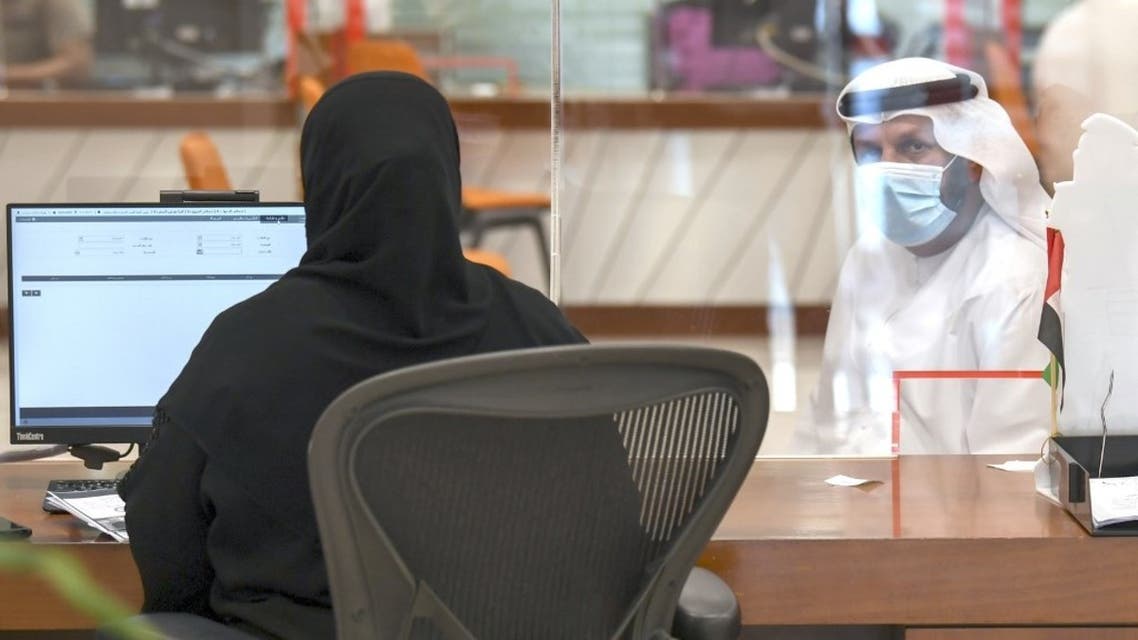 An Emiratia civil employee tends to a visitor at the Passports Department as government employees return to work following the easing of restrictions in Dubai on 16 June, 2020. (AFP)