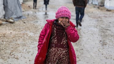 This handout photo released by Save The Children dated February 8, 2020 shows 9-year-old Syrian girl Zahira covering her face while walking amidst falling snow on a dirt path outside tents at a camp in the eastern countryside of Aleppo. (AFP)
