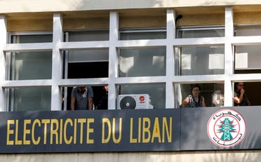 Employees of the Electricite du Liban (Electricity Of Lebanon) national company look out of their windows at students gathering for an anti-government demonstration outside, in the southern city of Sidon on November 6, 2019. (AFP)