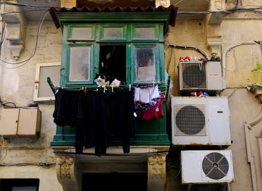 A cat sits in a balcony surrounded by hanging laundry and shoes on air conditioning units in Valletta. (Reuters)