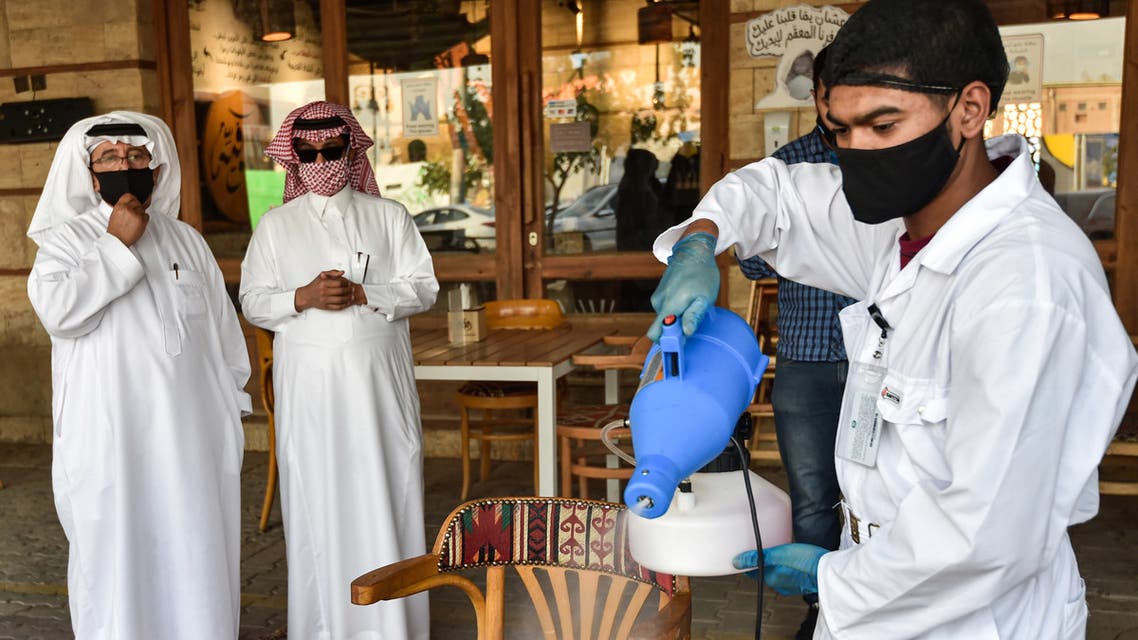 A latex glove-and-mask-clad worker sanitises a table for clients at a cafe in Saudi Arabia's capital Riyadh on June 21, 2020, as the country begins to re-open following the lifting of a lockdown due to the COVID-19 coronavirus pandemic.